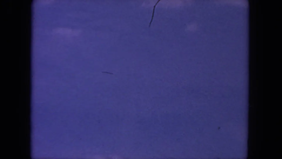 1962 8mm home-movie frame from San Diego metadata showing a mostly open purple-blue sky with faint clouds and visible film gate edges.