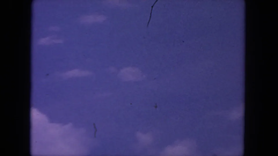 1962 8mm San Diego home-movie frame showing blue sky, puffy cloud edges, and visible film scratches.