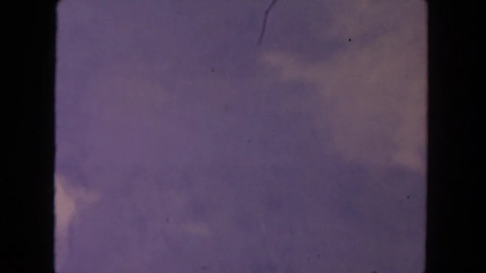 1962 8mm frame from San Diego travel footage showing hazy sky, faint clouds, and dark film gate borders.