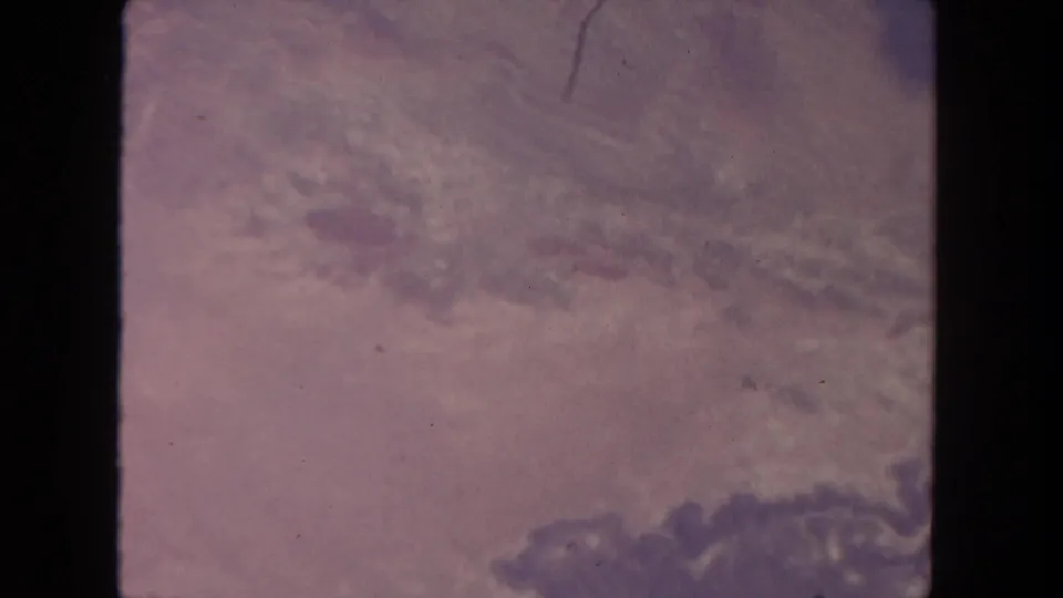 Vintage San Diego 8mm frame showing mottled cloud texture in pink-purple tones, with dust and vertical scratching.