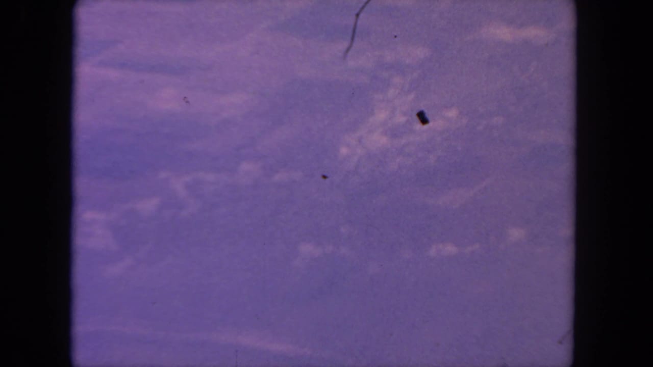 1962 San Diego-area 8mm frame showing pale branching water or stream patterns across purple-toned terrain with visible film dust.