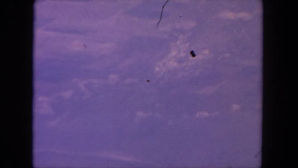 1962 San Diego-area 8mm frame showing pale branching water or stream patterns across purple-toned terrain with visible film dust.