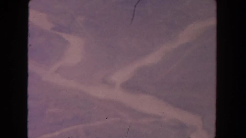 1962 San Diego-area 8mm frame showing soft purple terrain with pale streamlike bands and minor dust and scratches.