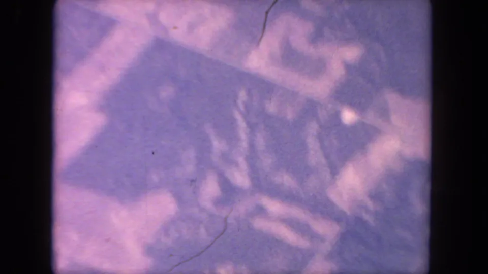 Purple-tinged 8mm frame that appears to show a distorted reflected or overhead street-grid pattern, with soft focus and visible film wear.