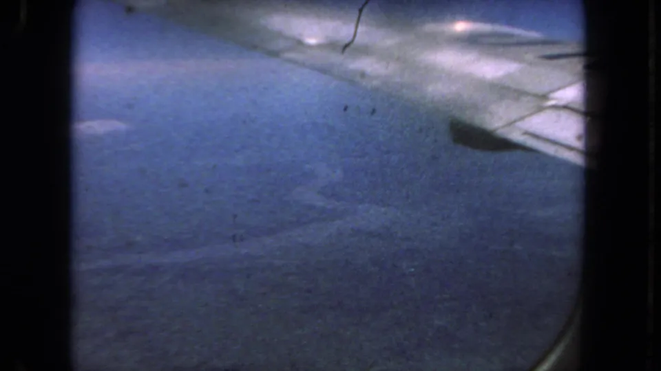 1962 San Diego 8mm frame showing blue-toned pavement, a pale curved road edge, moving shadows, and dark scan borders.
