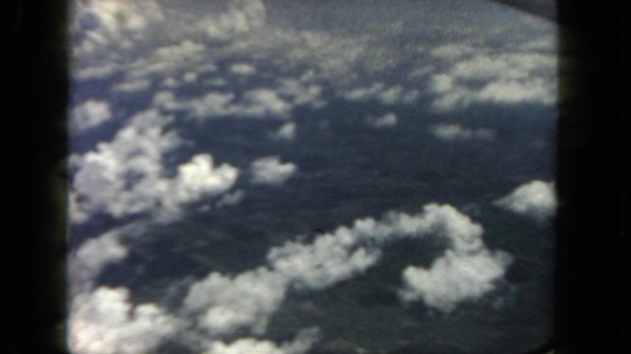 Bright cloud clusters over a darker surface, framed by black vertical film borders.
