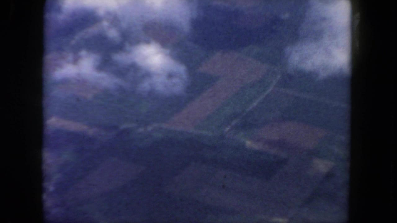 Cloudy aerial view with hazy ground shapes and dark 8mm frame borders.