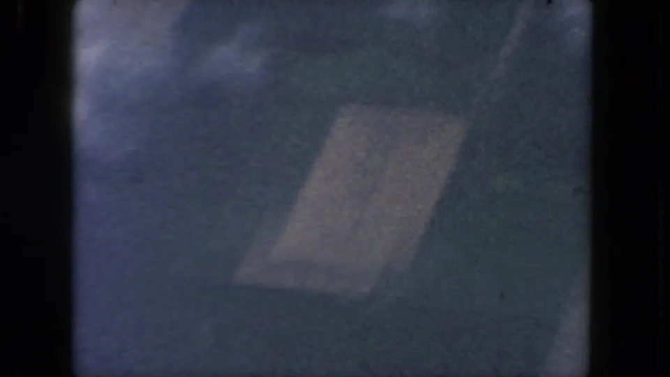 Soft 8mm aerial frame near San Diego with a faint rectangular land feature, hazy ground color, and visible frame edge.