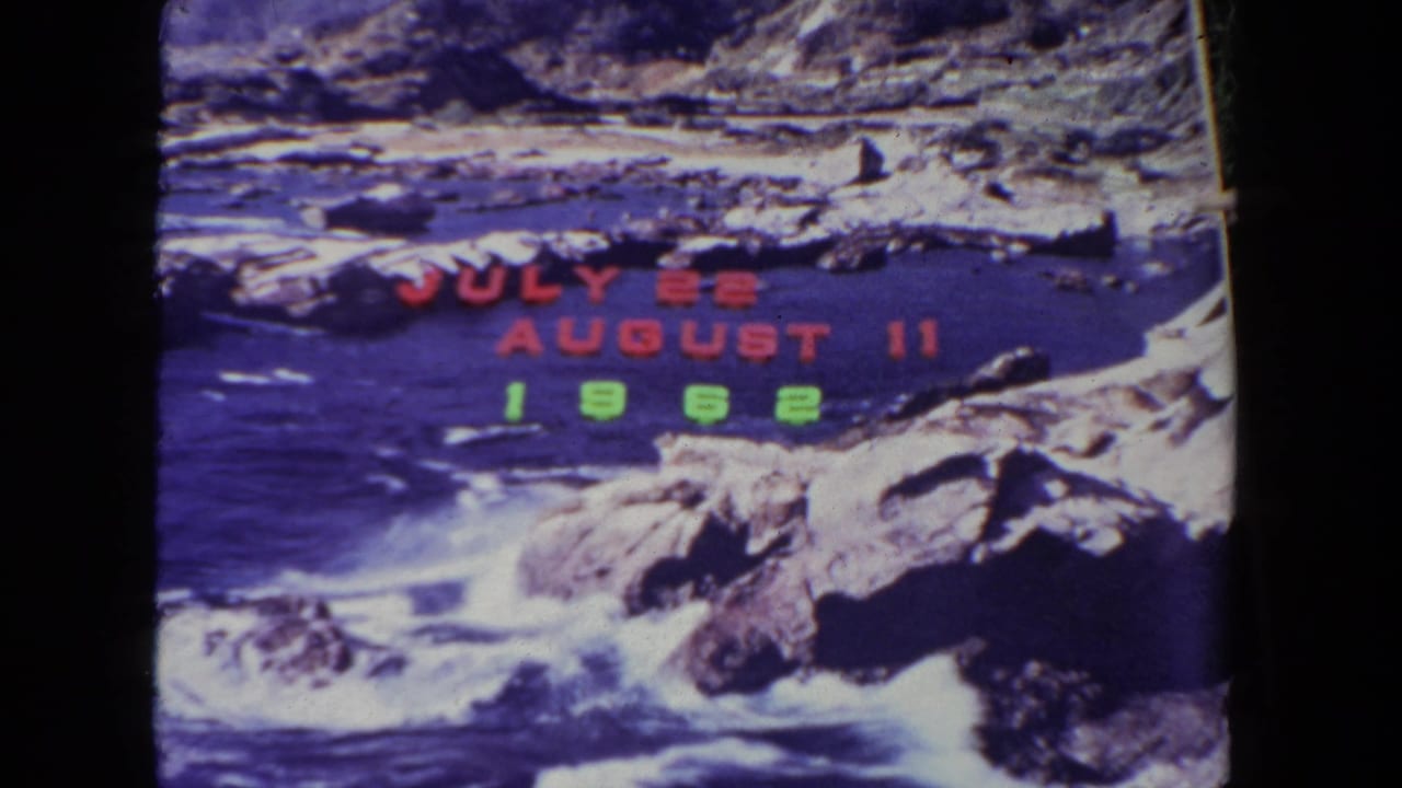 1962 8mm home-movie frame of a rocky coastal shoreline with waves and red-green date lettering over the view.