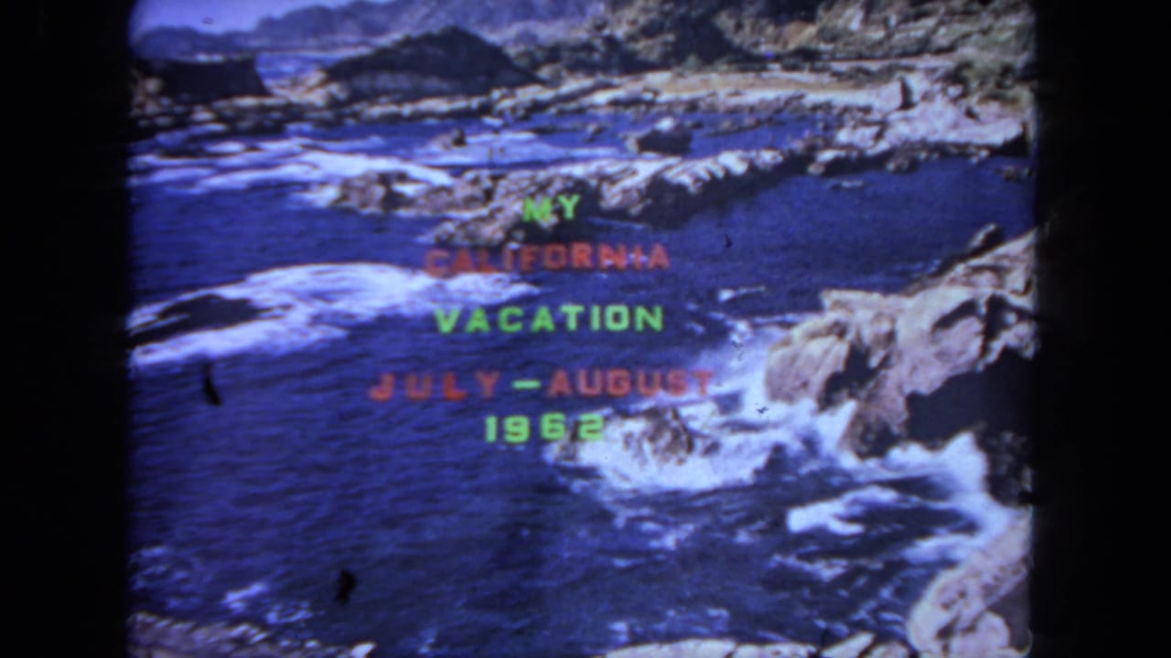 Vacation title card over blue water, rocks, and white surf along a coastal edge.