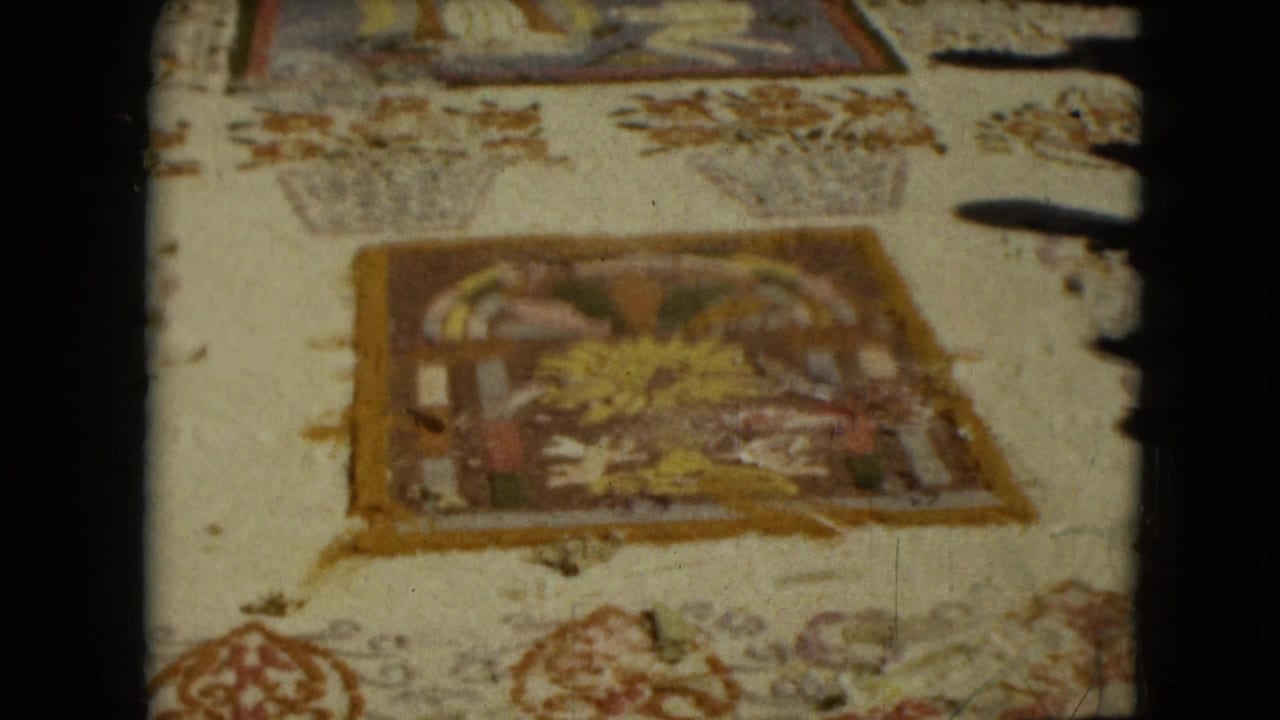 1962 Mexico City home-movie frame showing embroidered or woven religious art panels with floral decoration and warm faded colors.