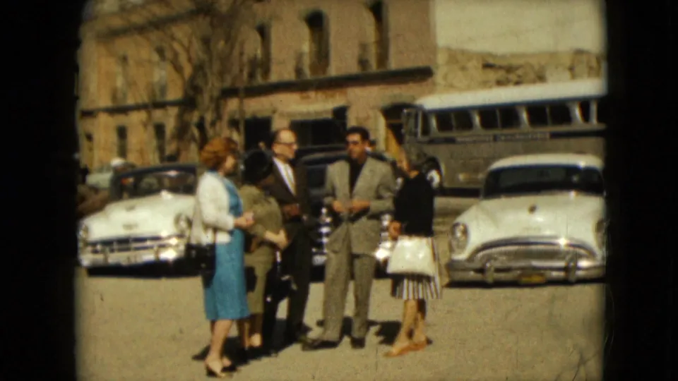 The home-movie camera records the group shifting during a Mexico City street conversation in 1962, with parked vehicles behind them.