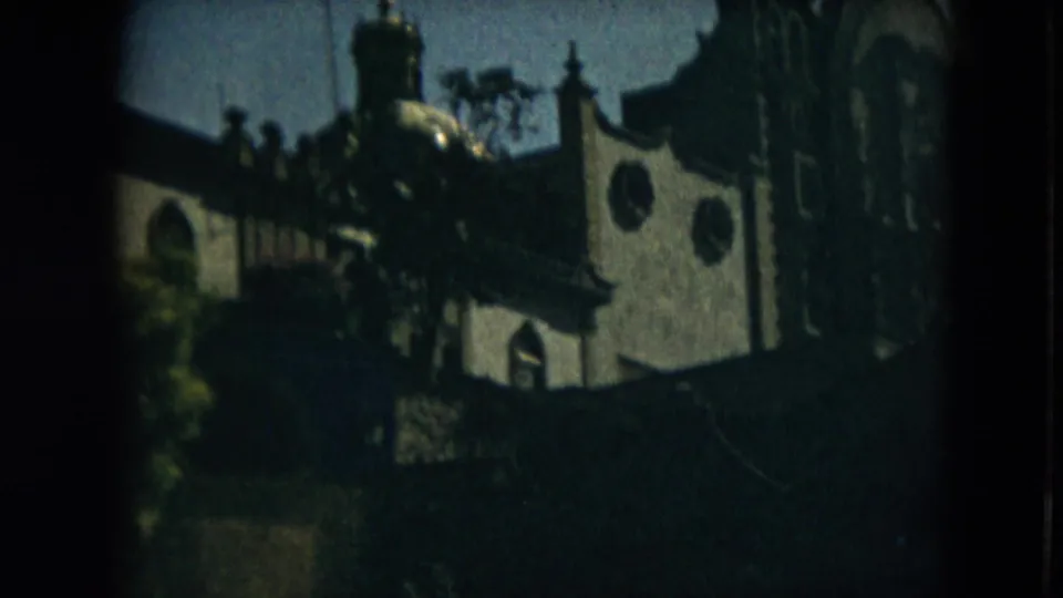Mexico City church exterior filmed on 8mm in 1962, showing circular windows and roof details through trees.