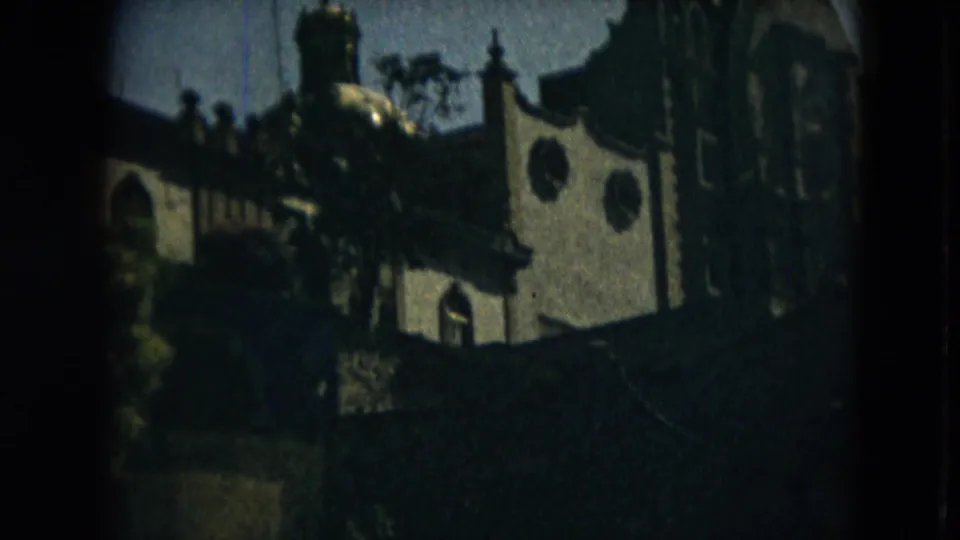 Soft 8mm frame of a Mexico City church facade in 1962, with arched and circular openings under trees.