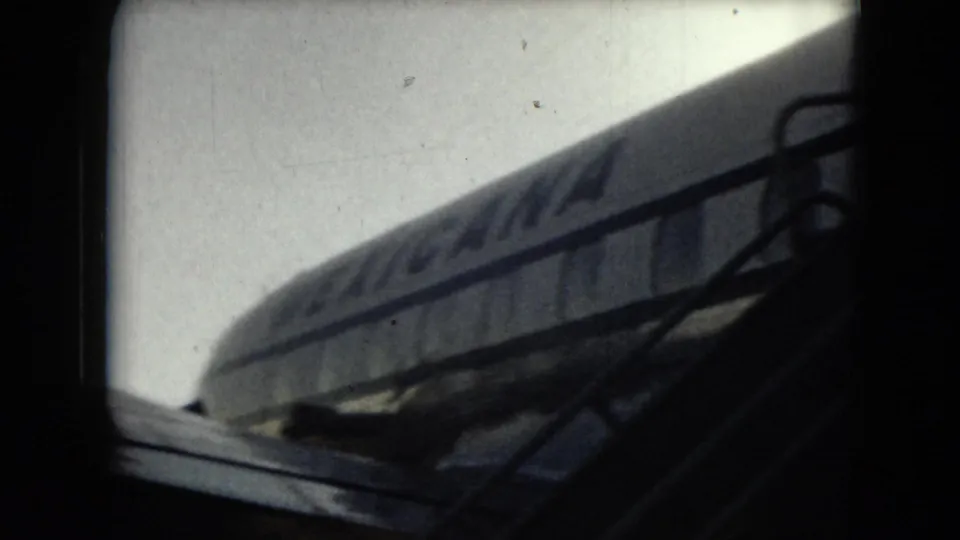 1962 Mexico City travel footage shows a parked airliner seen from a dark terminal or window-side vantage point.