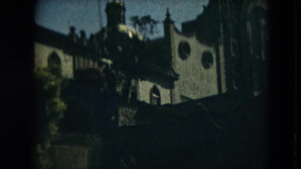 1962 Mexico City home-movie frame shows a domed building facade with arched windows and trees in low, grainy exposure.