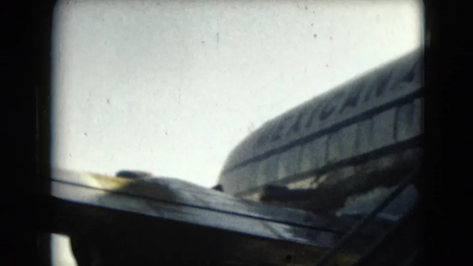 A soft 1962 8mm view shows part of a Mexicana aircraft tail and fuselage after the boarding moment.