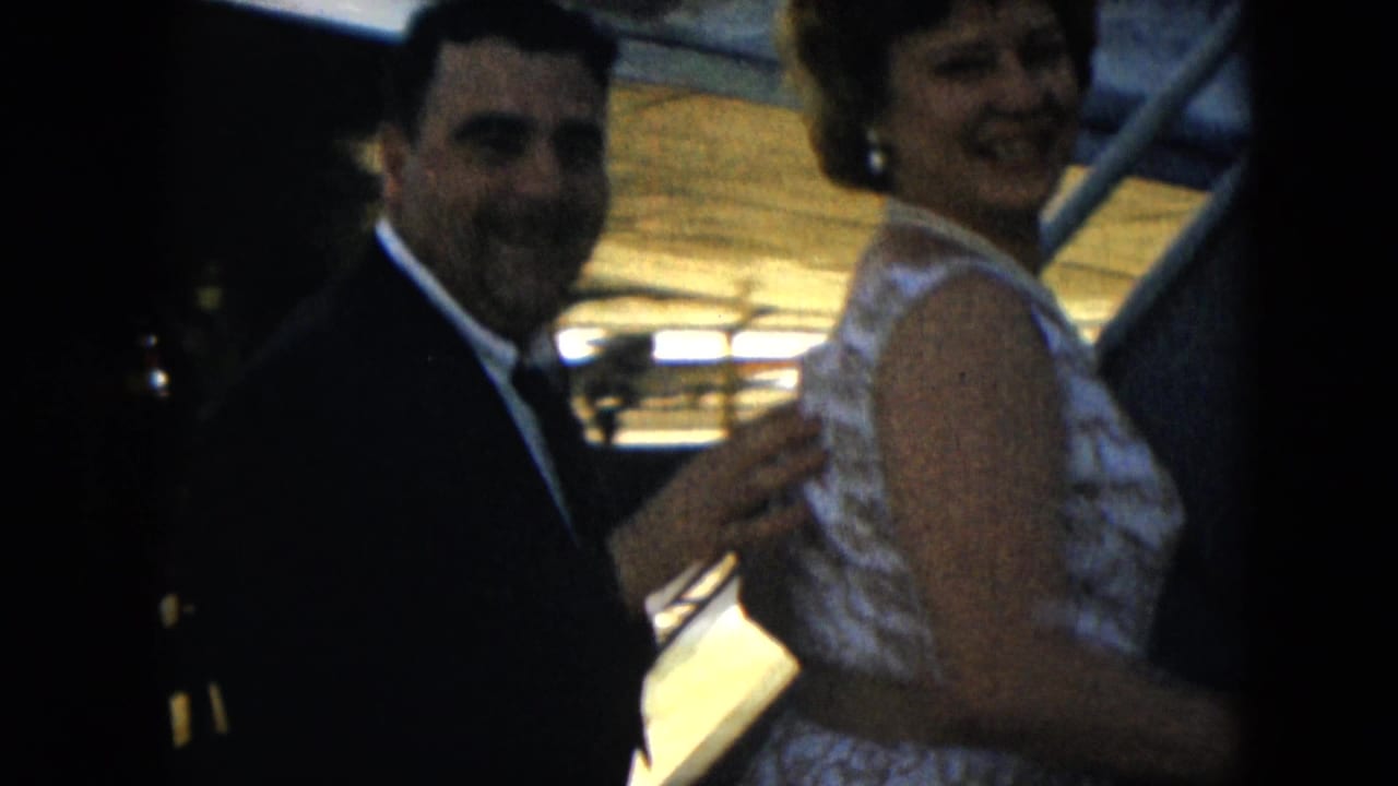 1962 Mexico City travel frame showing a smiling woman in a lace dress boarding aircraft stairs as a suited man follows.