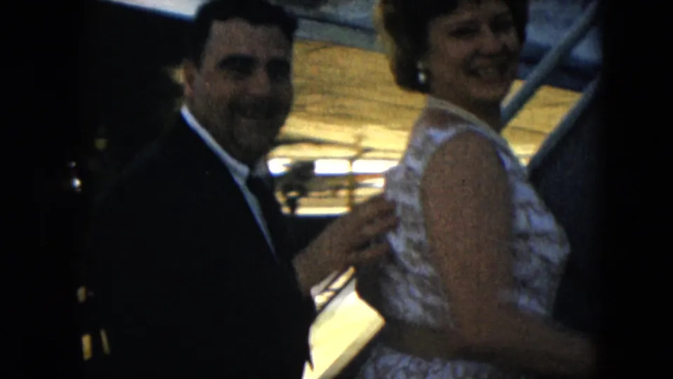 1962 Mexico City travel frame showing a smiling woman in a lace dress boarding aircraft stairs as a suited man follows.