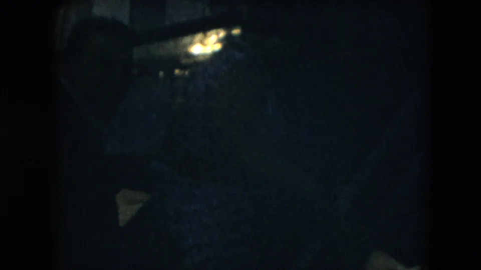 Underexposed 1962 home-movie frame with faint figures and aircraft boarding shapes barely visible in the dark image area.