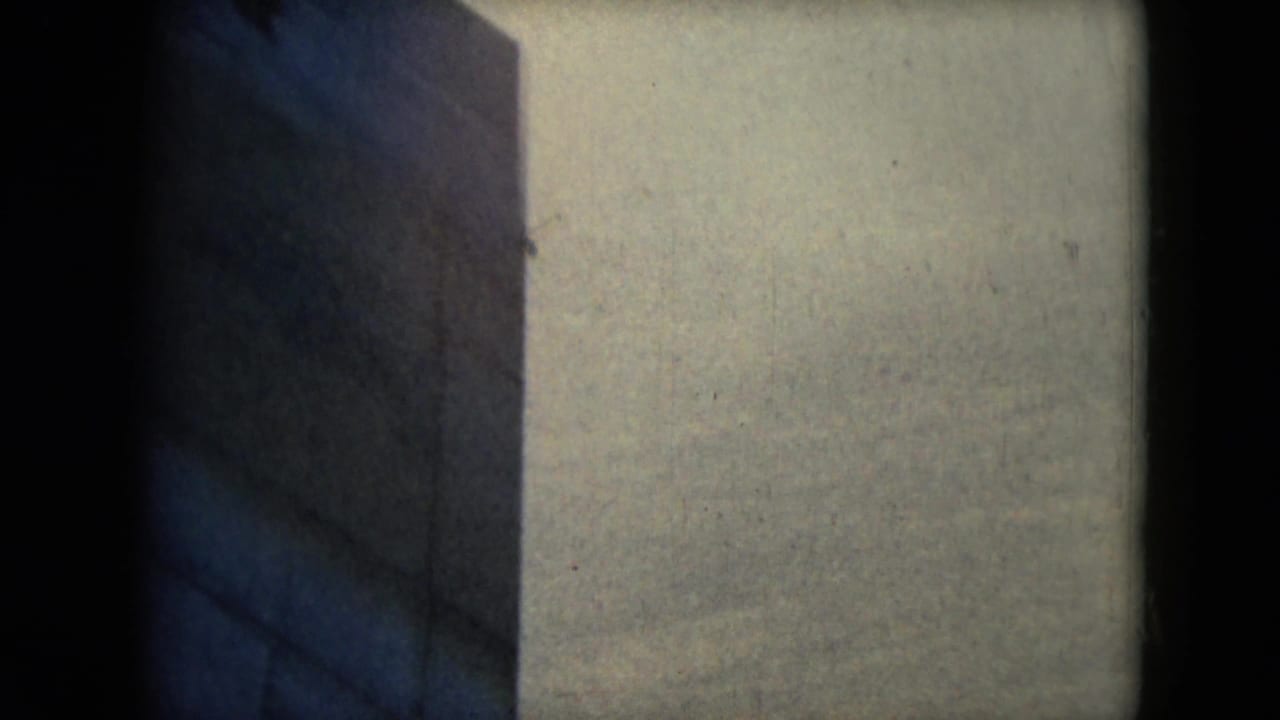 Blurred partial frame with a building wall and dark film edges.