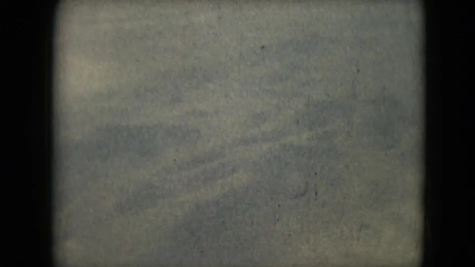 Grainy 1962 8mm frame showing soft, earth-toned terrain with rounded frame edges and faint wind-swept texture.