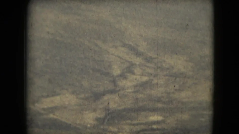 1962 8mm abstract frame showing a worn, softly focused textured surface with grain, faint streaking, and visible gate edges.