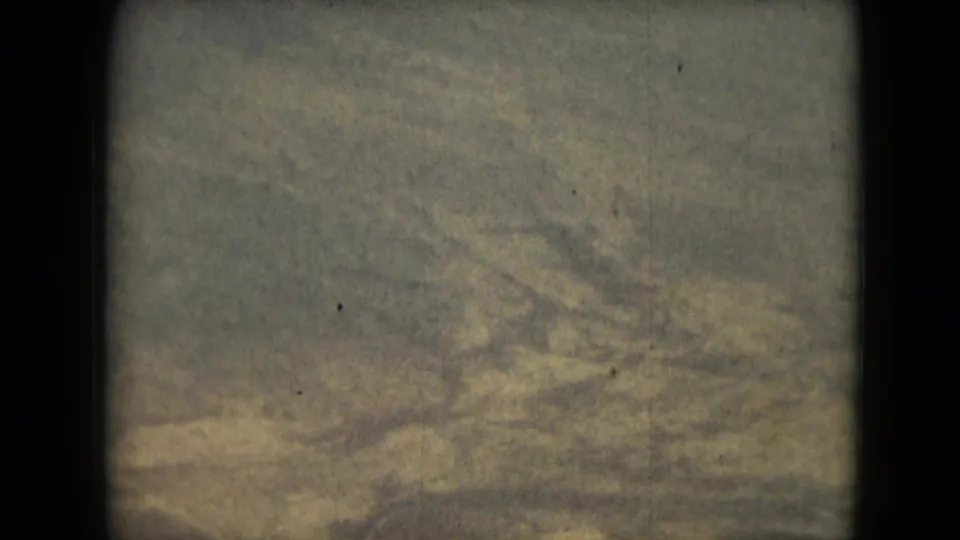 1962 8mm frame from Mexico metadata with broad, pale mountain textures seen from above and heavy archival grain.