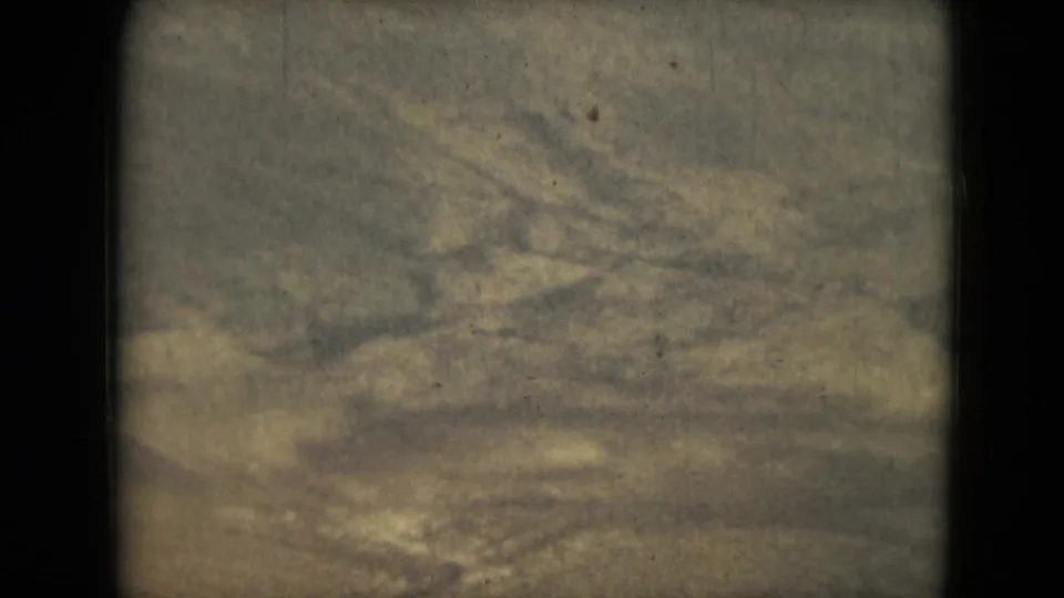 1962 8mm frame from Mexico metadata showing snowy slopes from above, softened by exposure shifts, dust, and film grain.