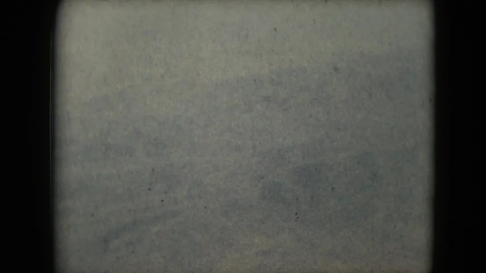 A 1962 Mexico-linked 8mm view of a pale mountain ridge and open terrain, softened by grain, haze, and dark gate edges.