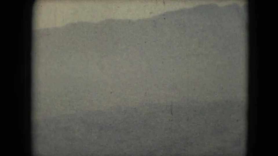 The 8mm frame shows a low mountain slope crossing the horizon above a muted foreground, with grain and border shadows from the scan.
