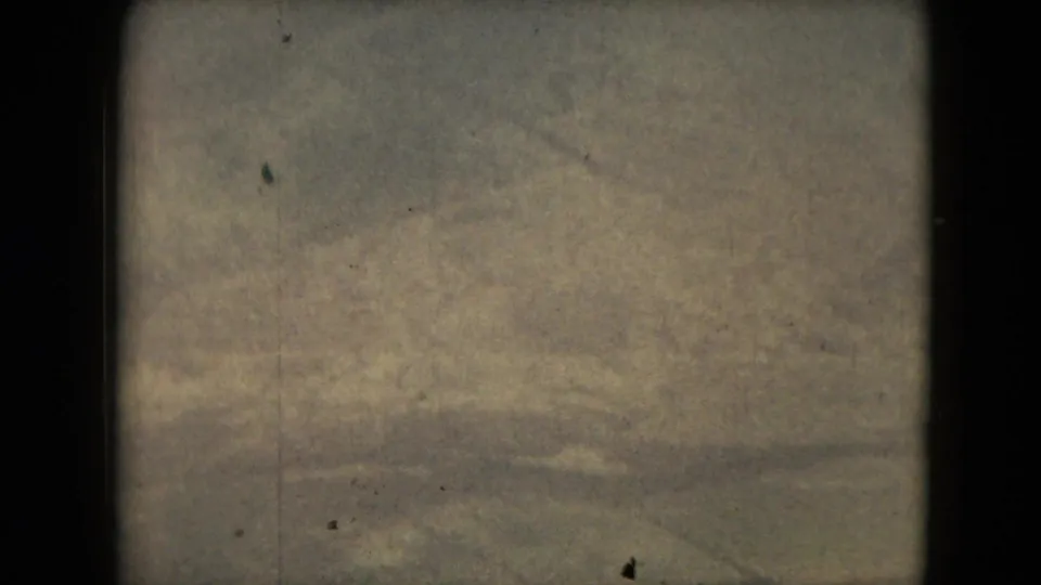 Final 1962 8mm frame shows indistinct terrain from high above, with visible dust, faded color, and no identifiable people or property.