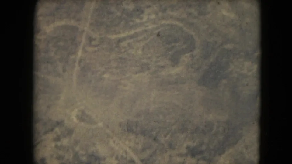 1962 8mm aerial-style view, tied to Mexico City metadata, showing indistinct rugged terrain with trees, pale paths, haze, and heavy grain.