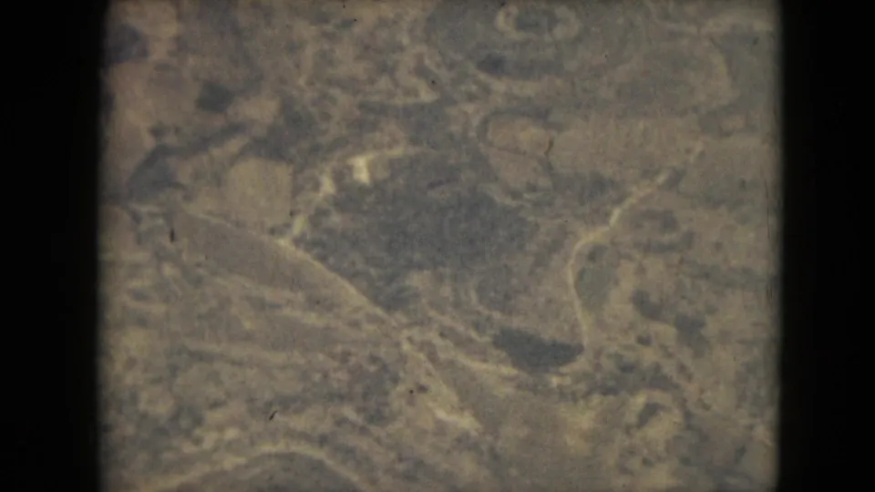 Soft 8mm aerial frame from 1962 metadata, possibly near Mexico City, showing indistinct brown-green terrain and curving path shapes.
