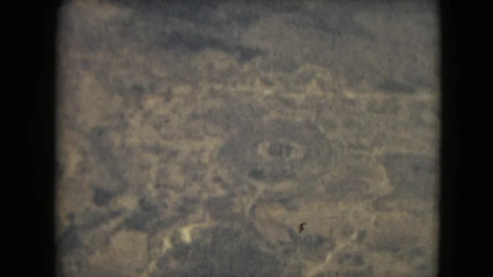 A hazy 1962 8mm aerial-style frame associated with Mexico City metadata, showing indistinct natural terrain without visible people or structures.