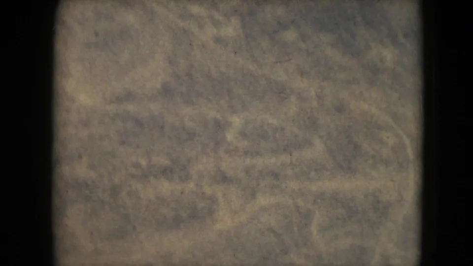 1962 8mm aerial frame from the Mexico City area showing muted scrubland, faint ground paths, and faded home-movie color.