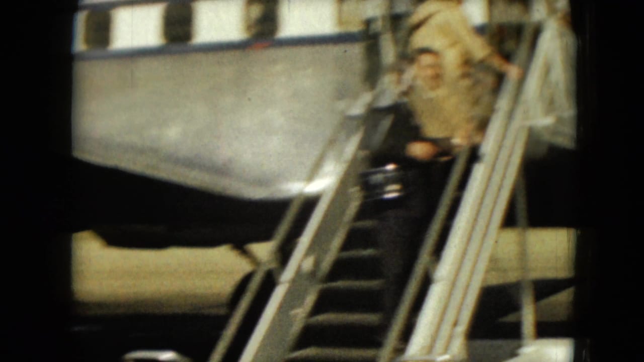 Adult passenger on metal stairs beside a silver airplane fuselage.