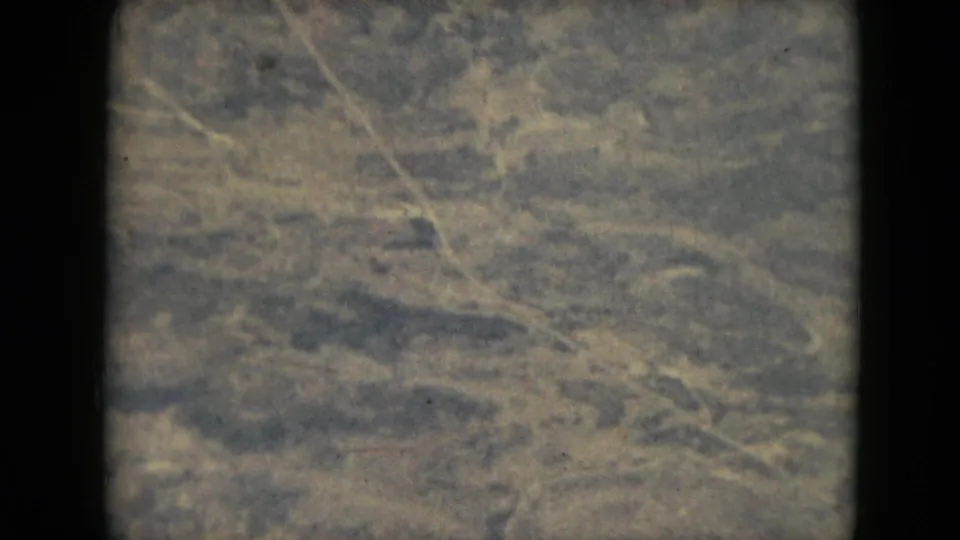 The clip shifts to a soft 8mm aerial view of patterned ground below during the flight.