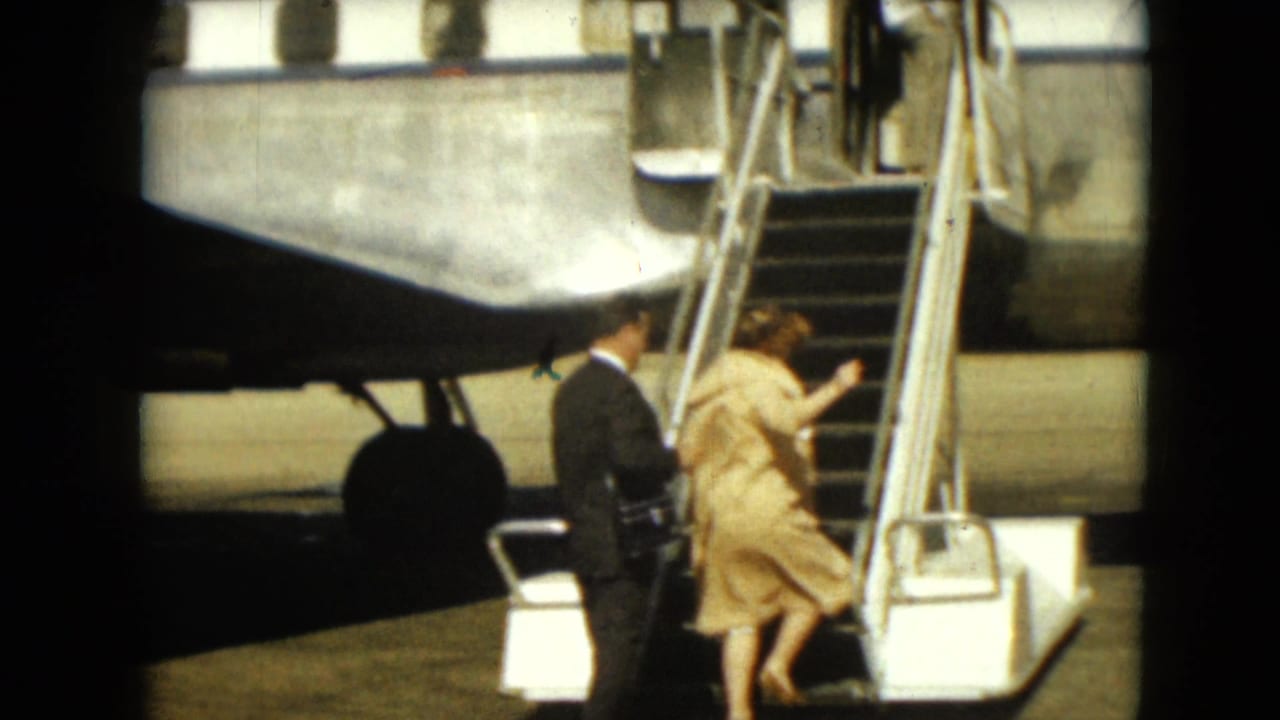 Man and woman begin climbing mobile stairs beside a passenger plane on the tarmac.