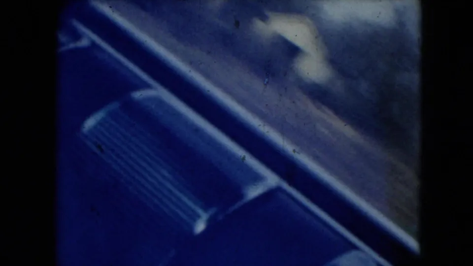 1962 Mexico City-area 8mm frame with blue-tinted vehicle trim or window detail in the foreground and blurred roadside landscape beyond.