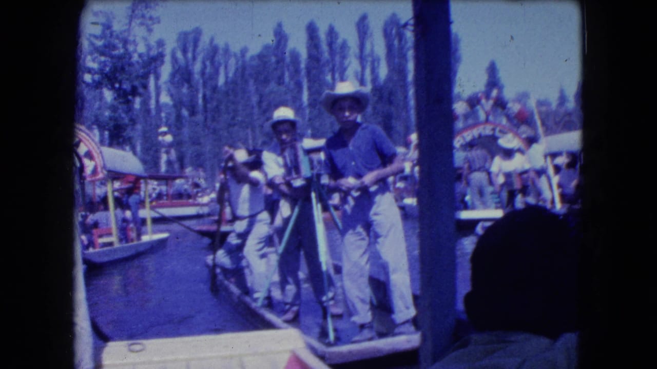 Two men with poles stand at the edge of a canal boat.