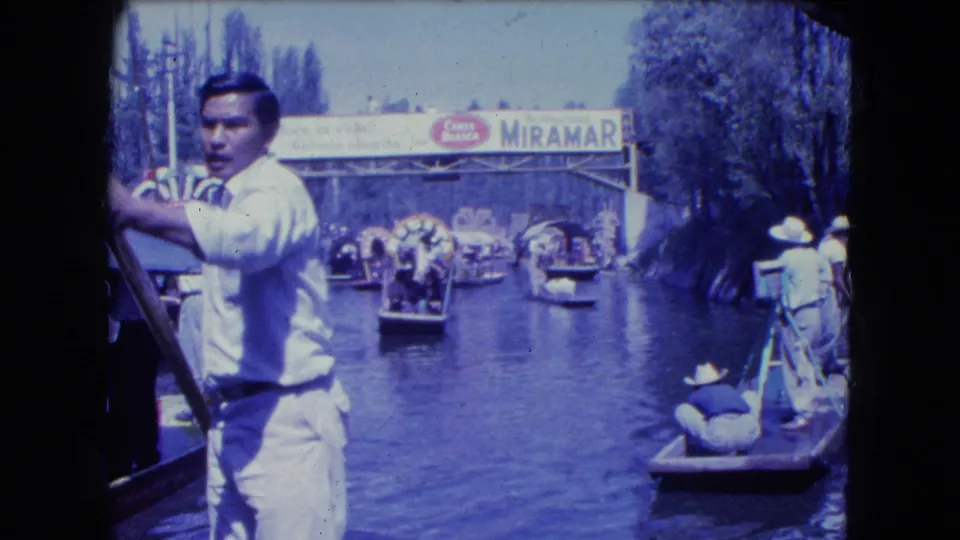 1962 Mexico City home-movie view from a boat, with a boatman in front and trajineras near a visible MIRAMAR sign.