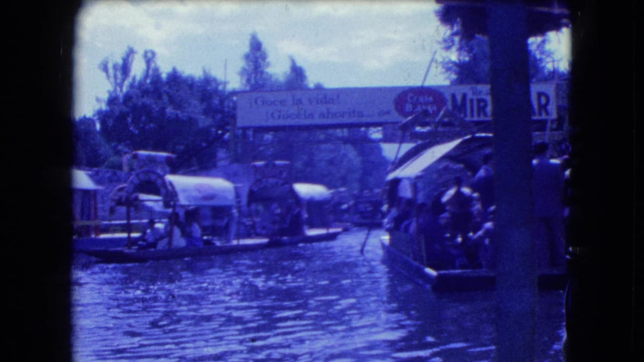1962 Mexico City canal footage showing several trajineras, passengers, trees, and a partially legible Spanish sign above the waterway.