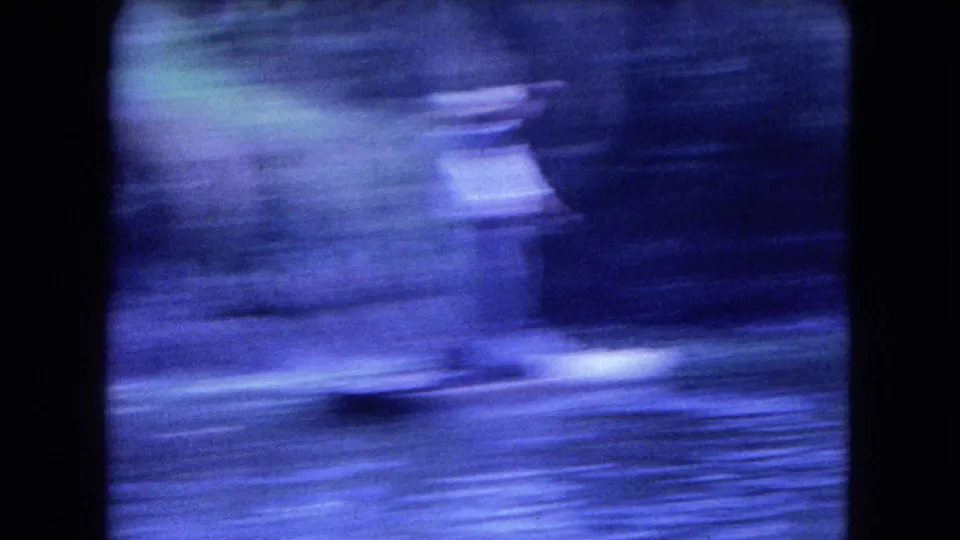 A motion-blurred 8mm frame from the Mexico City canal scene, with water, shoreline, and passing shapes rendered in blue color shift.