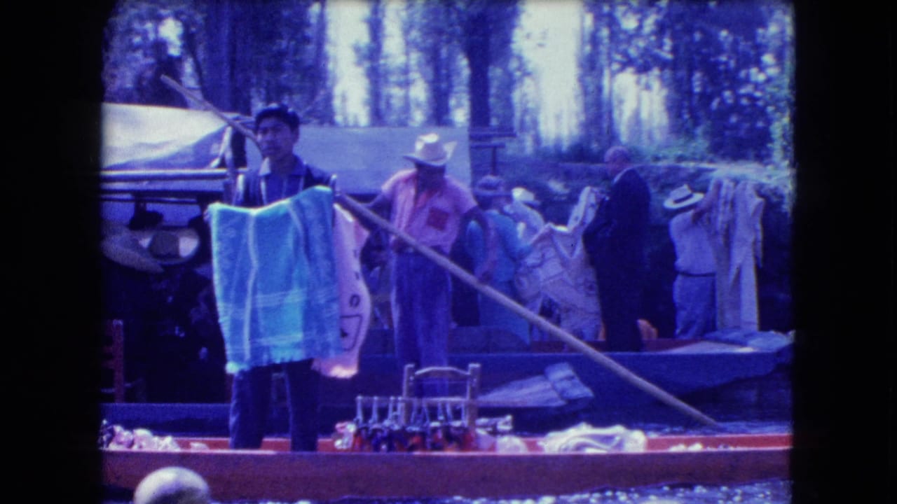 Several adults stand on and beside a canal boat with textiles and chairs.