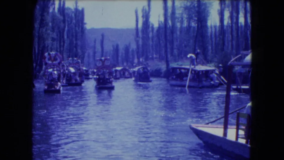 Mexico City canal footage shows clustered trajineras, passengers, and a docked boat near tall trees.