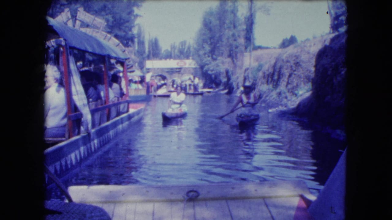 Mexico City canal footage shows paddlers and a covered passenger boat passing along a narrow waterway in 1962.