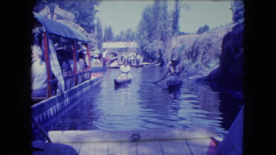 Mexico City canal footage shows paddlers and a covered passenger boat passing along a narrow waterway in 1962.