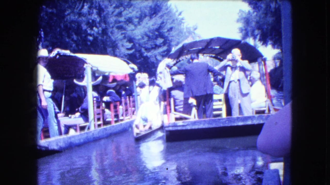 1962 Mexico City canal-tour footage showing passengers in period clothing on covered boats along a narrow waterway.