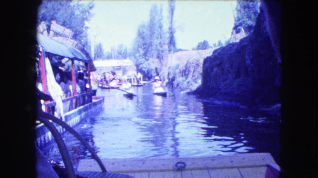 View from a boat looking down a canal with other small boats ahead.